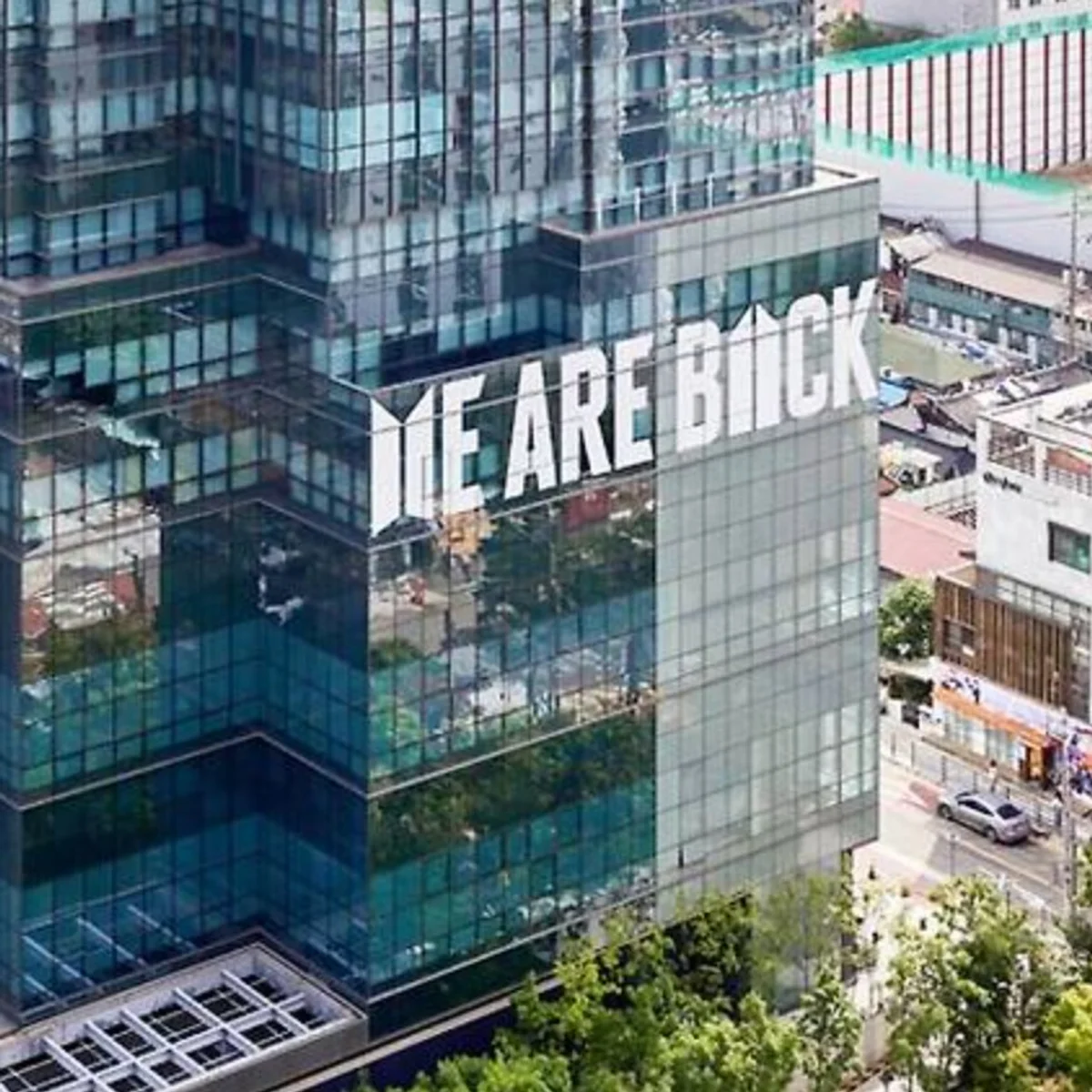 HYBE's headquarters in Yongsan, Seoul, is wrapped with BTS and ARMY’s official logos and the phrase "WE ARE BACK." The display is part of "BTS FESTA," celebrating BTS's June 13 debut anniversary with fans